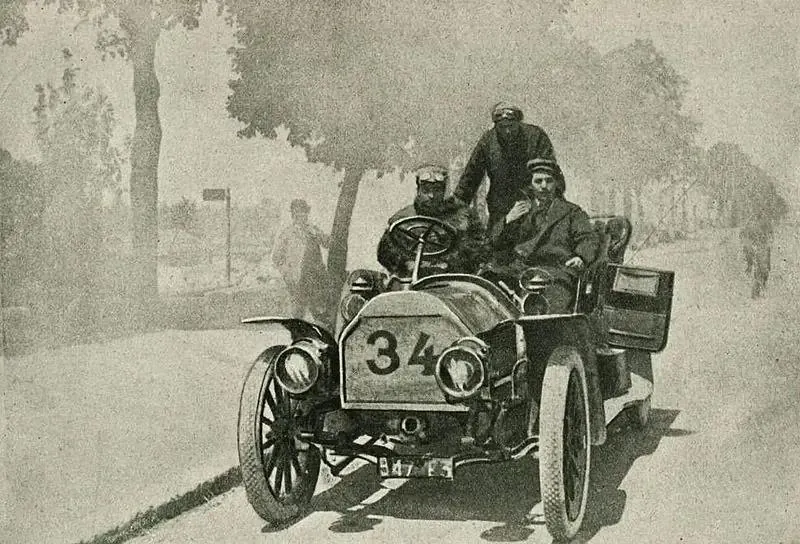 Racing car with number 34 and two occupants on a tree-lined road, early 20th century
