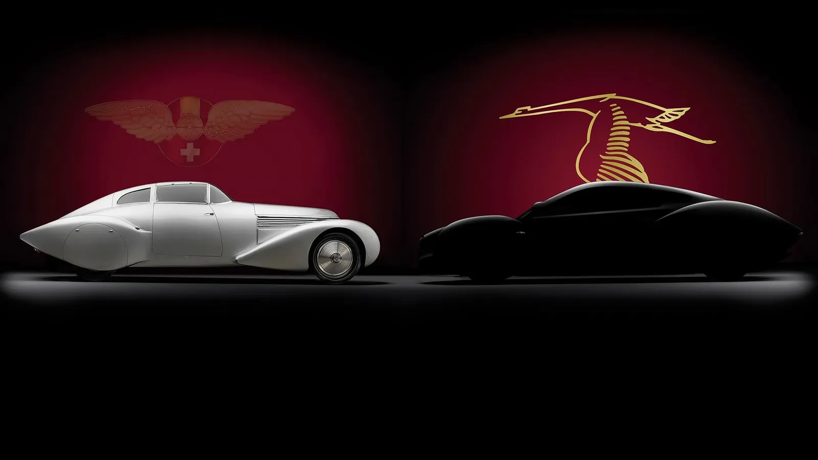 Dos automòbils Hispano-Suiza de disseny aerodinàmic, un de clàssic platejat i un de modern negre, sobre fons vermell fosc