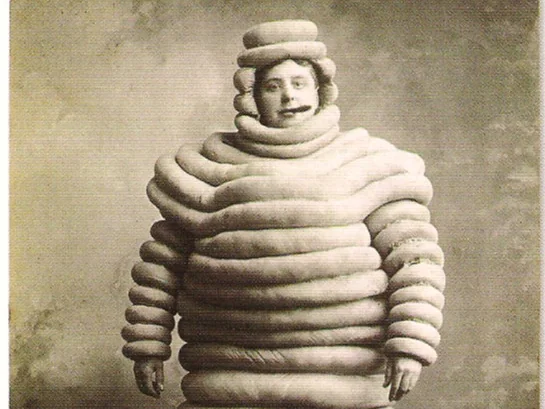 Old photograph of a man in a costume made of tyres, like the Michelin Man