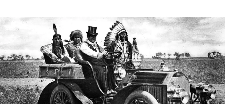 Group of gentlemen in top hats and plumes in a vintage car in the countryside
