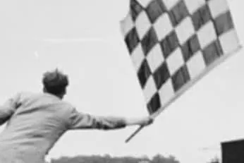 Jutge de cursa agitant una bandera de quadres blancs i negres, en fotografia en blanc i negre